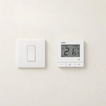 ENGO E7 thermostat in white on a wall next to a light switch